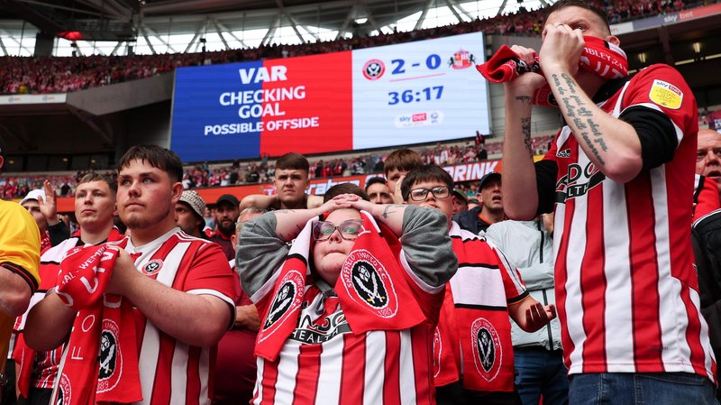 Dozens of Sheffield United fans, mostly dressed in red and white club shirts, look on in anguish in the lower tier behind the goal at Wembley Stadium during the Championship play-off final moments before their second goal against Sunderland was disallowed by VAR for offside.
