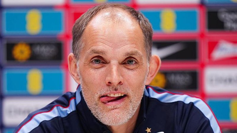 Head and shoulders view of England head coach Thomas Tuchel at a news conference, with his tongue poking out of his mouth