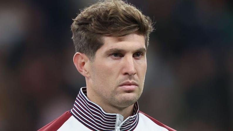 Head and shoulders view of John Stones in a zip-up England tracksuit top