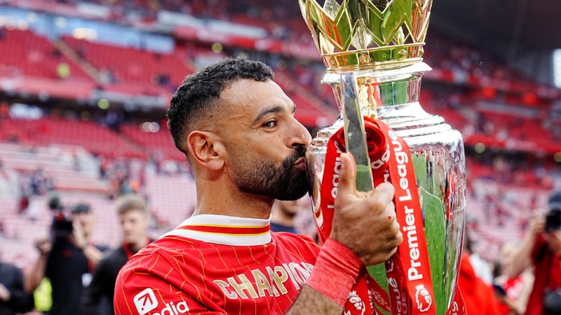 Liverpool winger Mohamed Salah kisses the Premier League trophy after his side's title win in 2024-25.