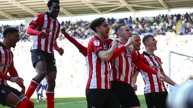 Jack Moylan is embraced by Lincoln City team-mates after scoring the goal that sealed victory against Reading and promotion to the Championship