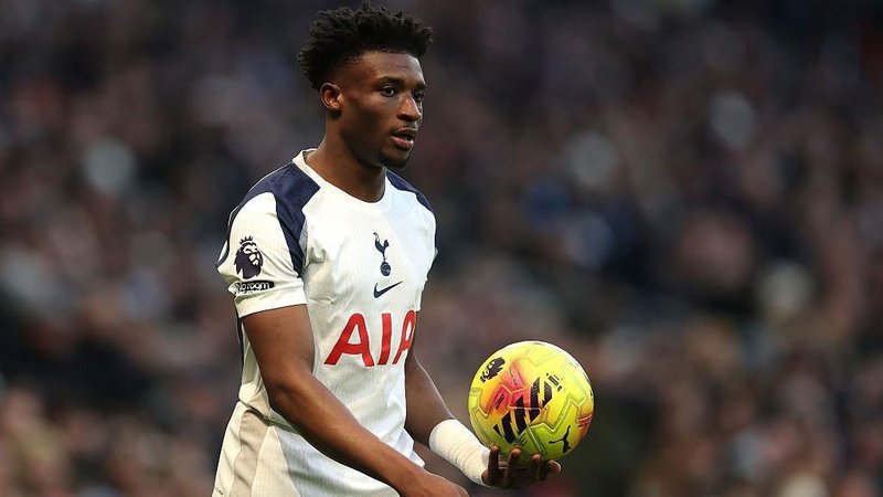 Mohammed Kudus holds the ball in his hand. He wears the white of Tottenham.