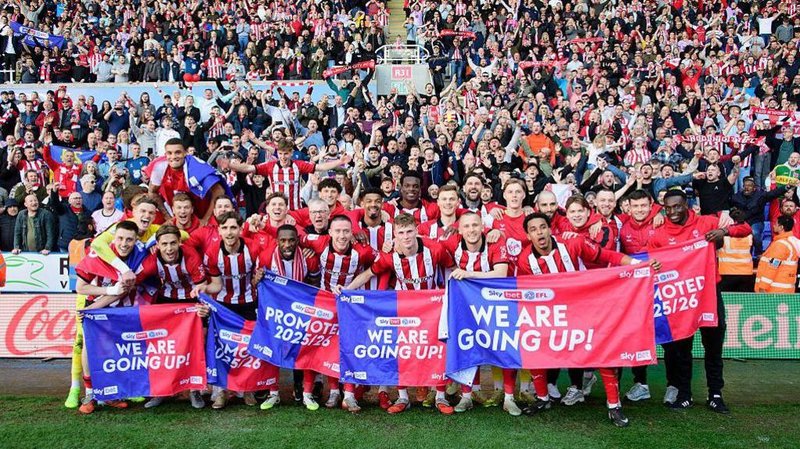 The Lincoln City squad celebrating their promotion in front of their visiting supporters at Reading's Select Car Leasing Stadium.