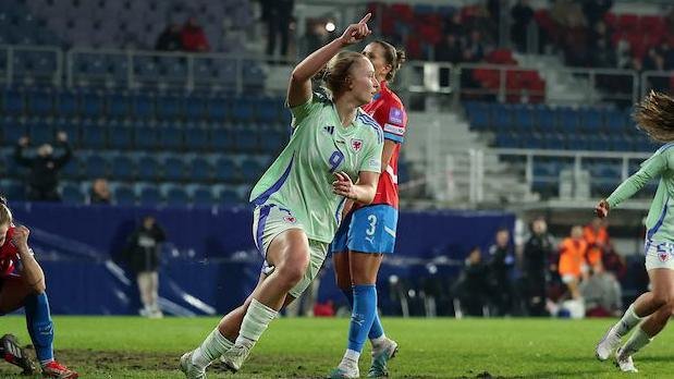 Wales' Elise Hughes, in Wales' light green away kit, celebrates with her right arm raised and a finger pointing