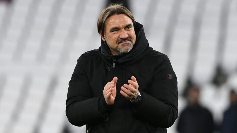 Daniel Farke, wearing a black coat and smiling, applauds at the end of Leeds' FA Cup quarter-final 