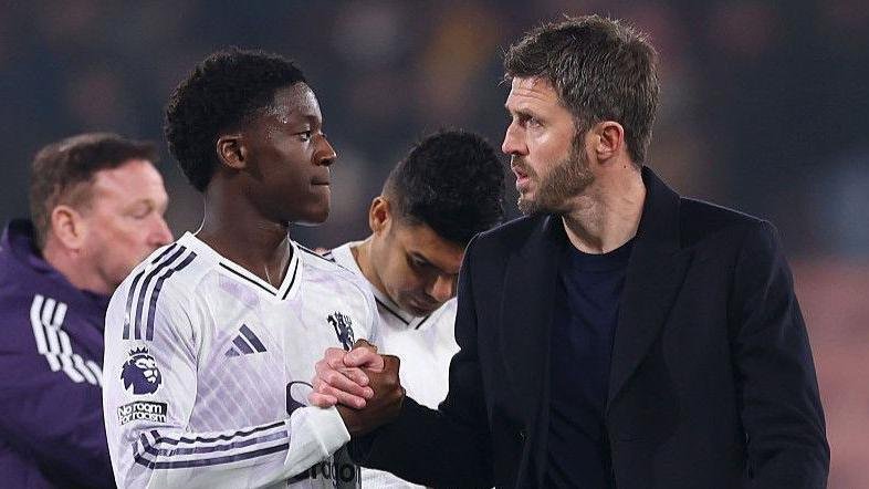 Manchester United head coach Michael Carrick (right) shakes hands with Kobbie Mainoo