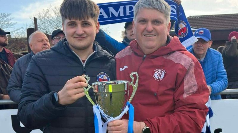 Lee Hayward poses with the United Counties League Premier Division South trophy with his son James 