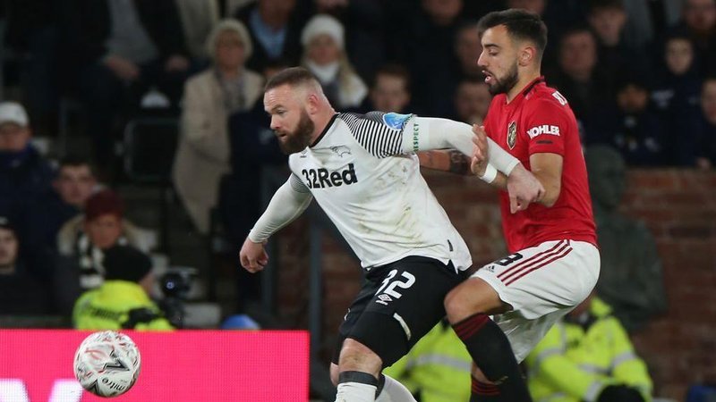 Wayne Rooney and Bruno Fernandes battle for the ball