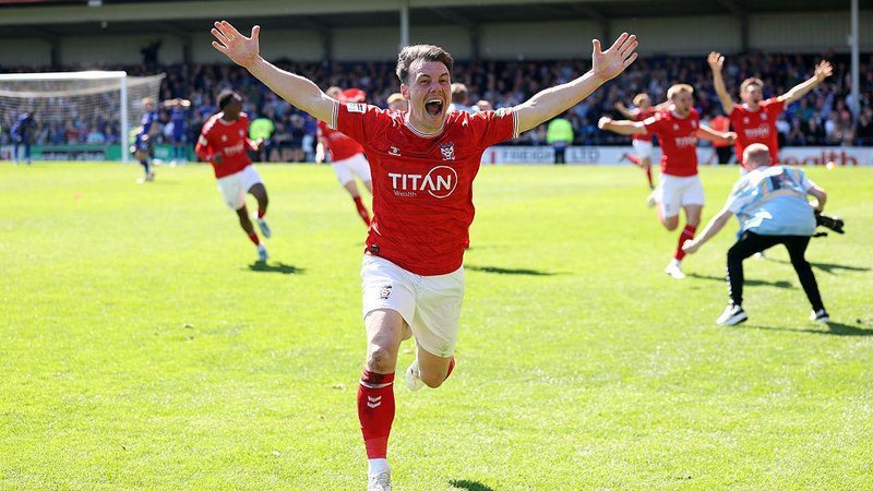 Ryan Fallowfield of York City celebrates after teammate Josh Stones scored to equalise and secure the team's promotion against Rochdale