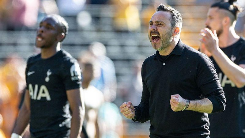 Roberto de Zerbi, in a black long-sleeved polo shirt, celebrates with fists clenched as he shouts and looks happy
