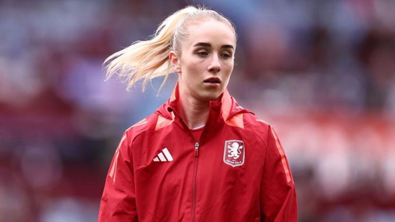 Missy Bo Kearns wearing a red jacket with an Aston Villa badge on the chest