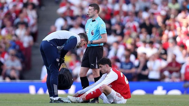 Kai Havertz sits on the pitch while a physio stands over him after injuring himself against Newcastle  