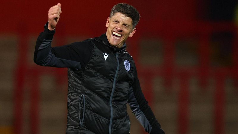 Stevenage Borough boss Alex Revell raises his right arm in celebration and he has led them to the League One play-offs.