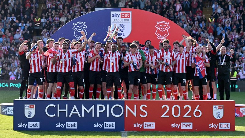 Lincoln players celebrate with the League One trophy