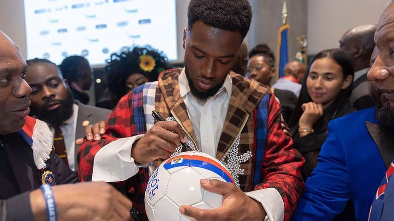 Duckens Nazon signs a football
