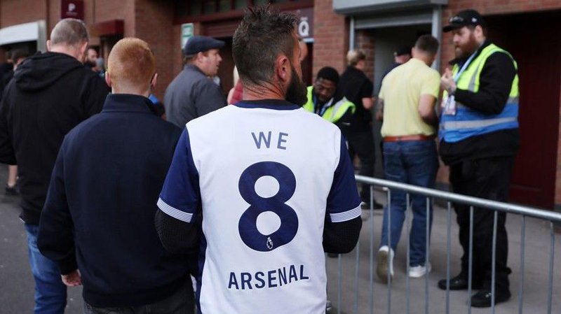 A Tottenham fan wearing shirt saying 'We 8 Arsenal'