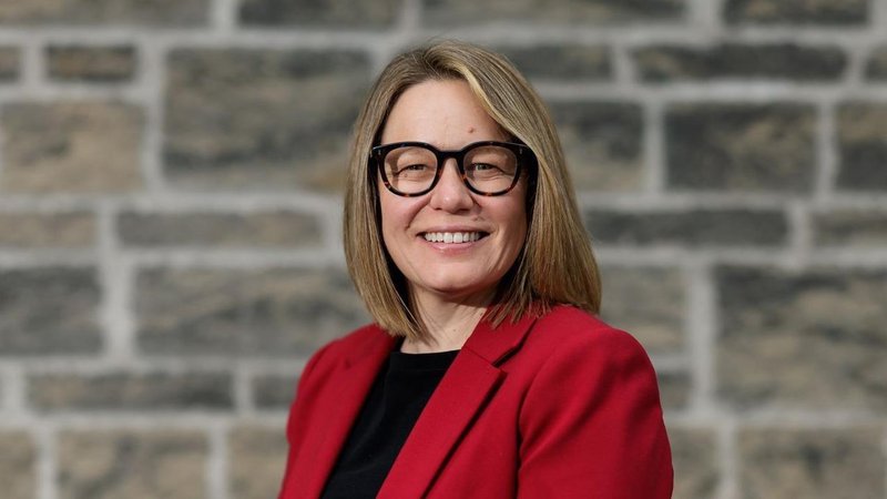 Hannah Buckley wearing a red blazer smiles and looks at the camera