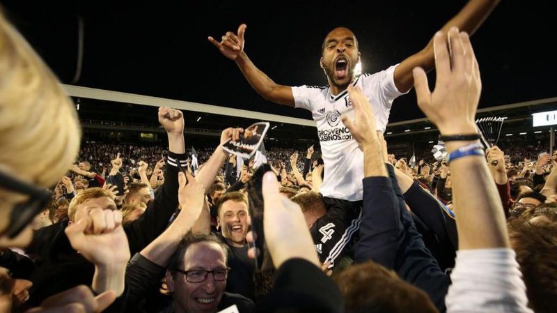 Fulham's Denis Odoi is hoisted aloft by Fulham fans on the pitch at Craven Cottage