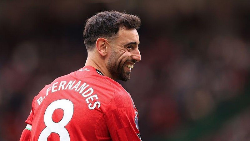 Manchester United captain Bruno Fernandes smiles as he wears the club shirt with the number 8 and his name - B. Fernandes - on the back