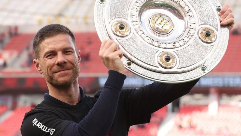 Bayer Leverkusen head coach Xabi Alonso hold aloft the German Bundesliga trophy in 2024