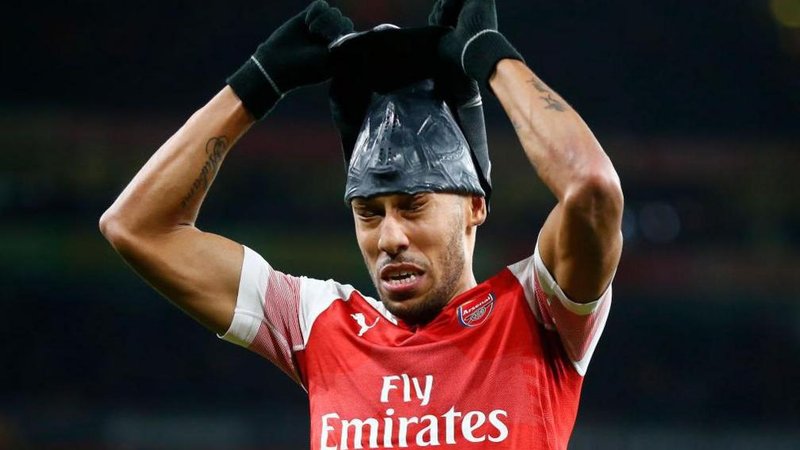 Arsenal striker Pierre-Emerick Aubameyang tries to remove a Black Panther mask after scoring for the Gunners.