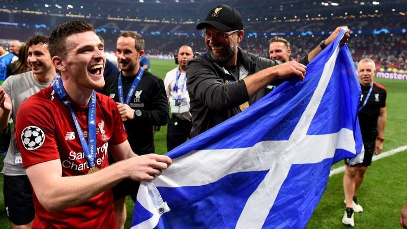 Andy Robertson and Jurgen Klopp hold a Scotland flag during 2019 Champions League celebrations.