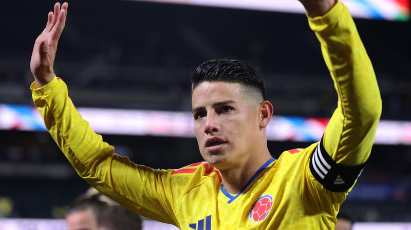 James Rodriguez of Colombia acknowledges fans with both arms raised as he wears yellow kit